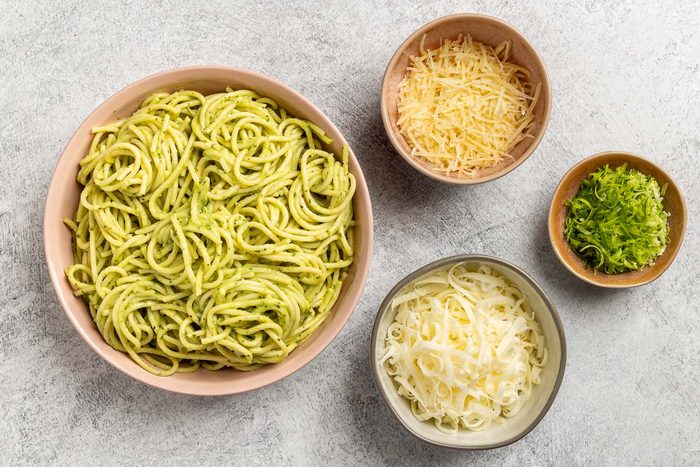 Taste of Home Avocado Pesto recipe photo of the pasta and additional toppings including shredded mozzarella, Parmesan and lime zest.