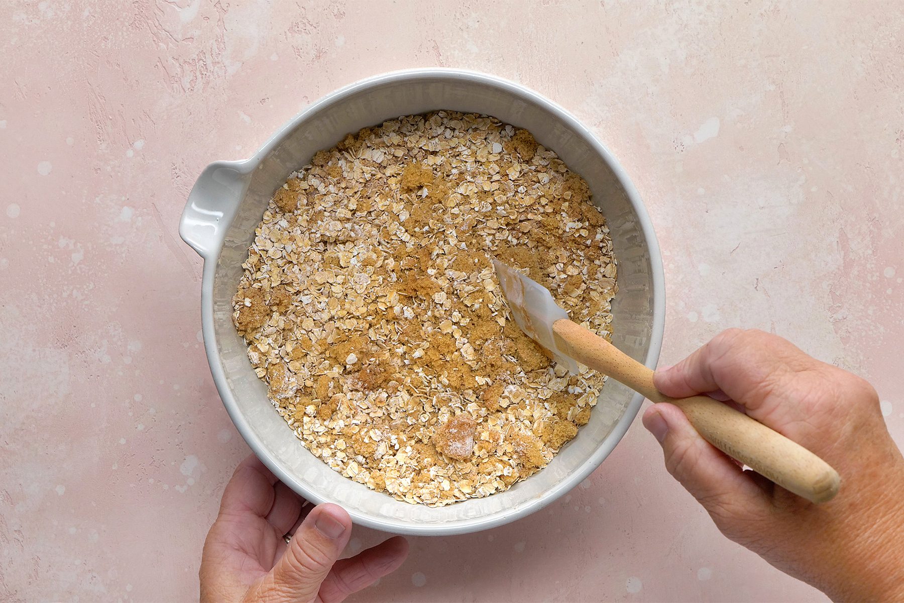 overhead shot; light peach background; In a large bowl, combining oats, brown sugar, baking powder, salt and cinnamon;
