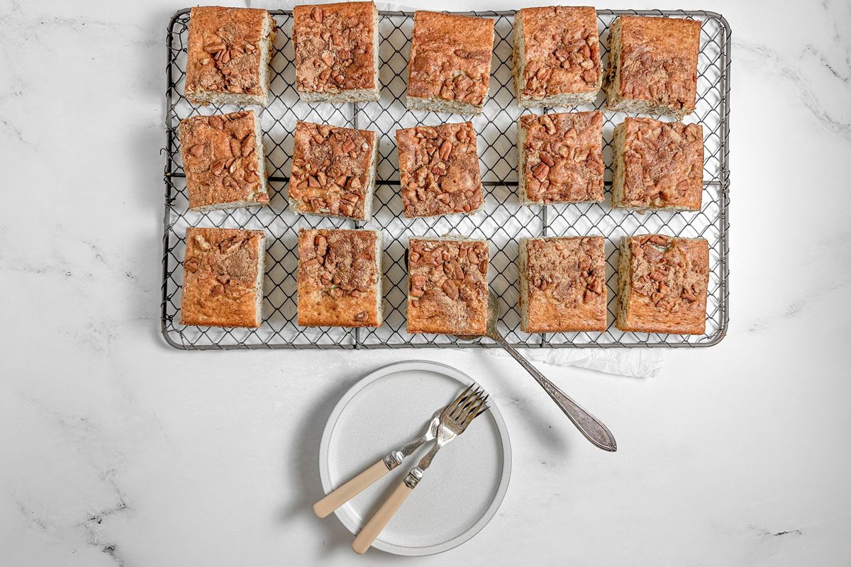 Taste of Home Banana Coffee Cake on wire rack with white plates on a marble surface
