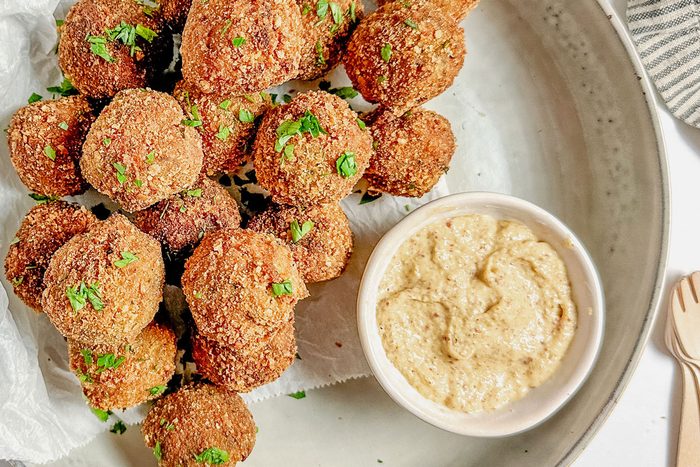 Taste of Home Bitterballen with a bowl of mustard set in a ceramic bowl on a marble surface.