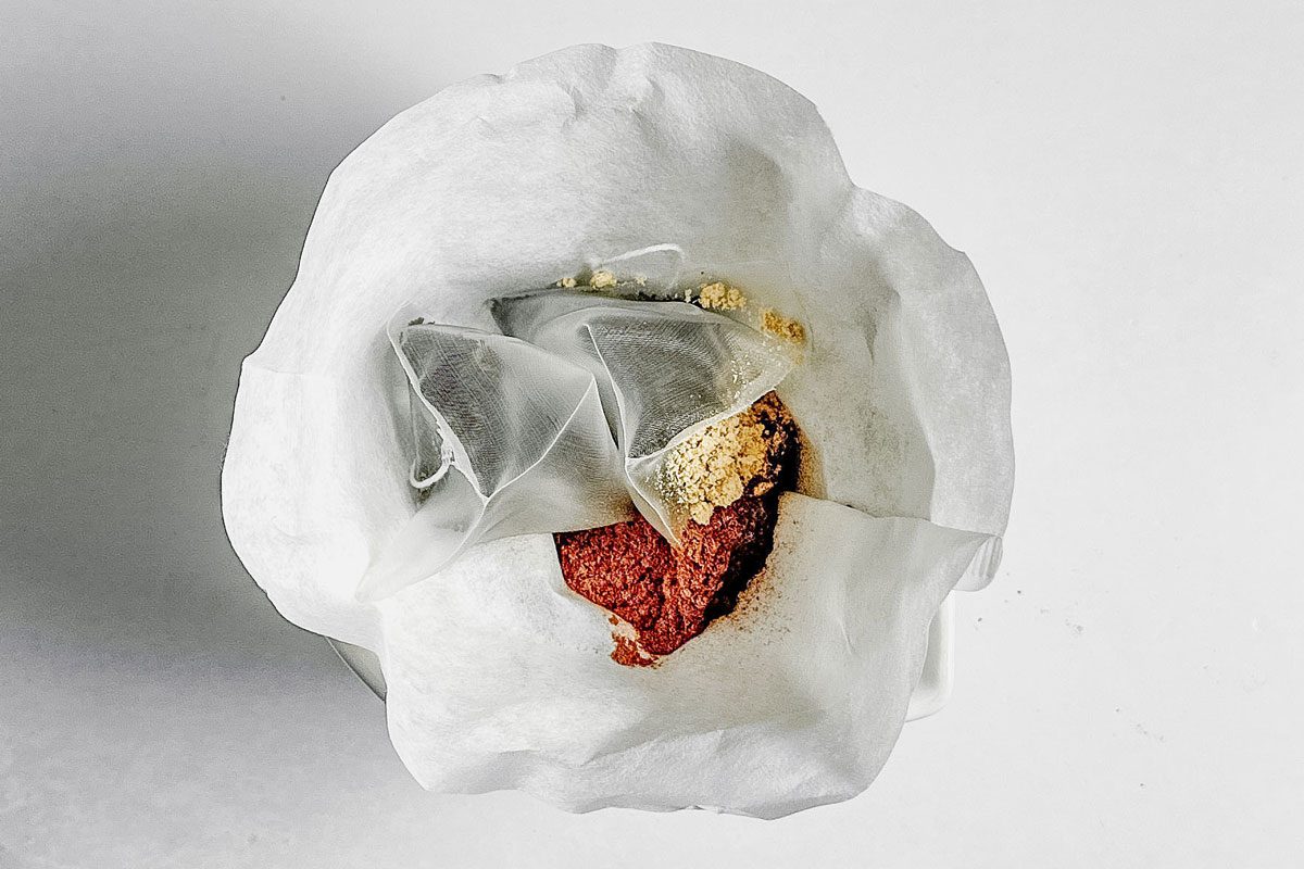 Ingredients for Taste of Home Chai Tea Latte in a coffee filter on a marble surface.