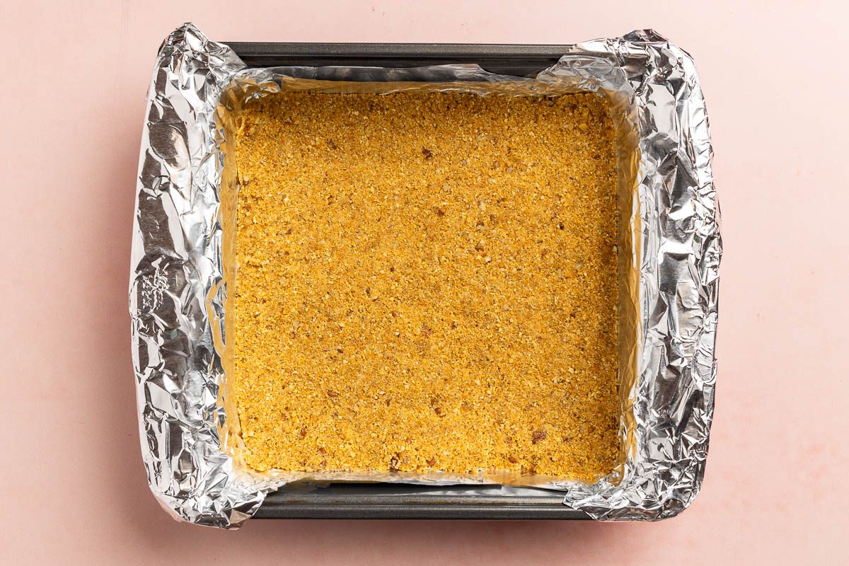 Taste of Home Cheesecake Bites recipe photo of the graham cracker crust in a 9 inch square baking pan.