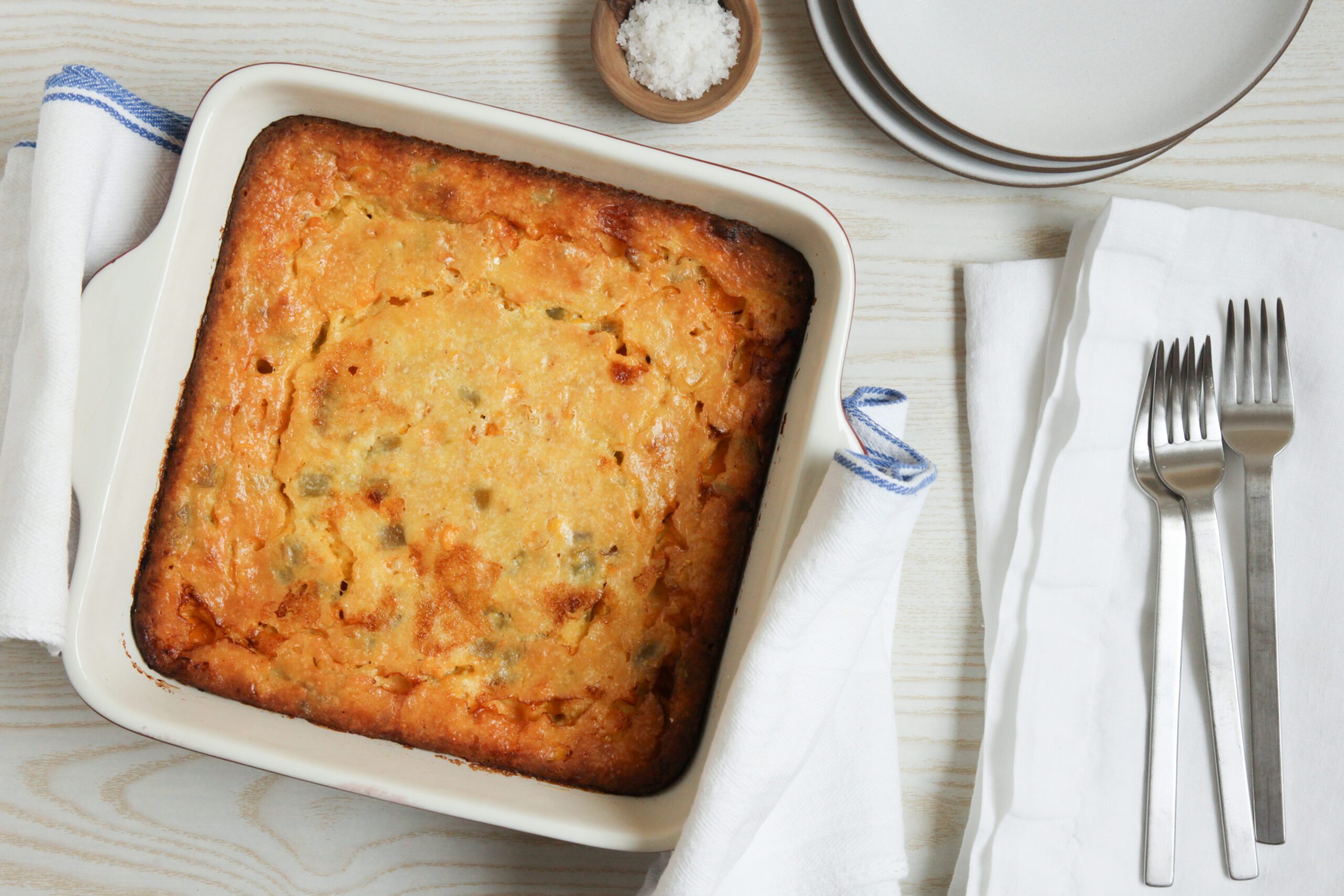 Cheesy Corn Casserole with plates and utensils