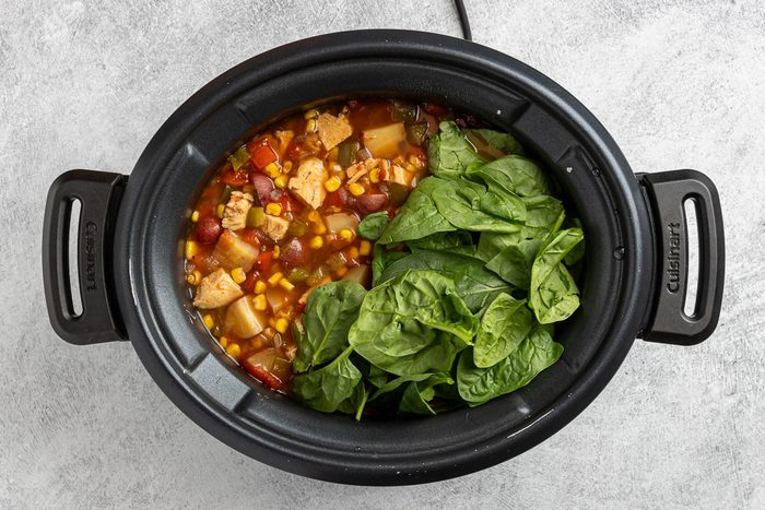 Taste of Home Crockpot Chicken Vegetable Soup recipe photo of the cooked soup with the fresh spinach added to the crockpot.