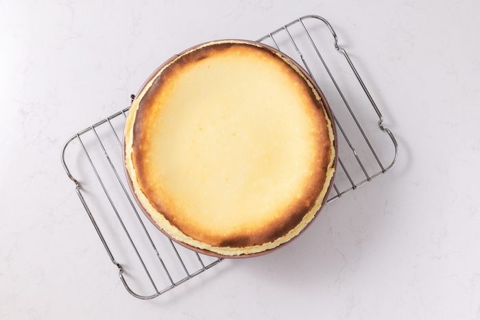 Cheesecake baked and cooling in wire rack.