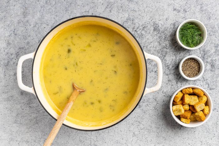 Taste of Home Dill Pickle Soup recipe photo of the milk added to the soup with fresh dill, fresh cracked pepper and croutons for garnish.