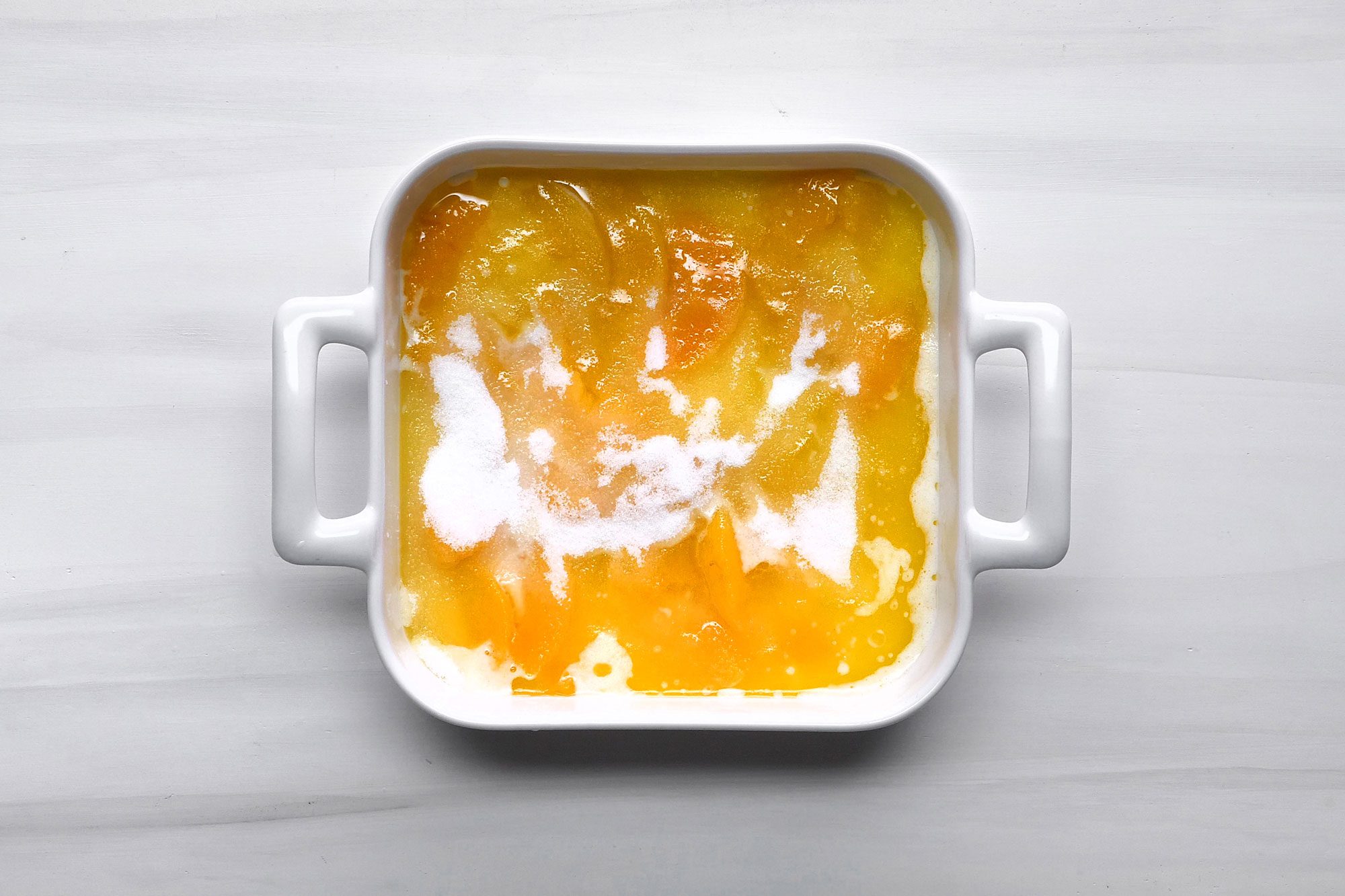 overhead shot; white background; Spoon hot peaches over batter; Sprinkled with remaining sugar;