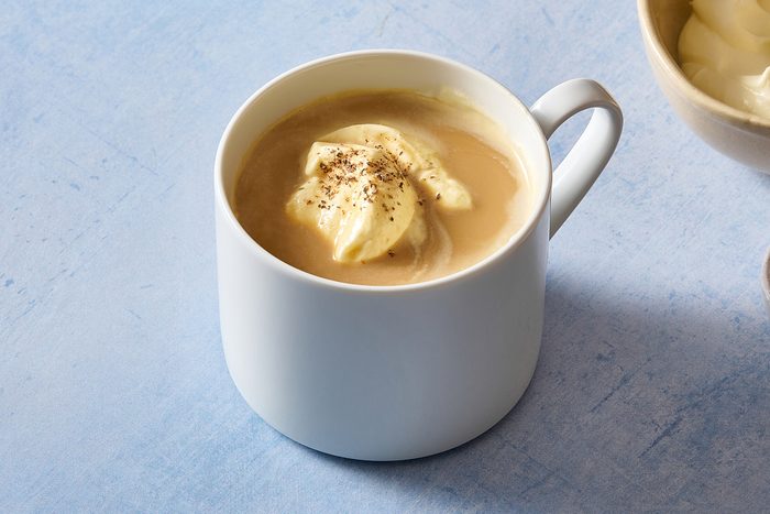 Closeup of a mug of eggnog coffee topped with shipped cream and nutmeg