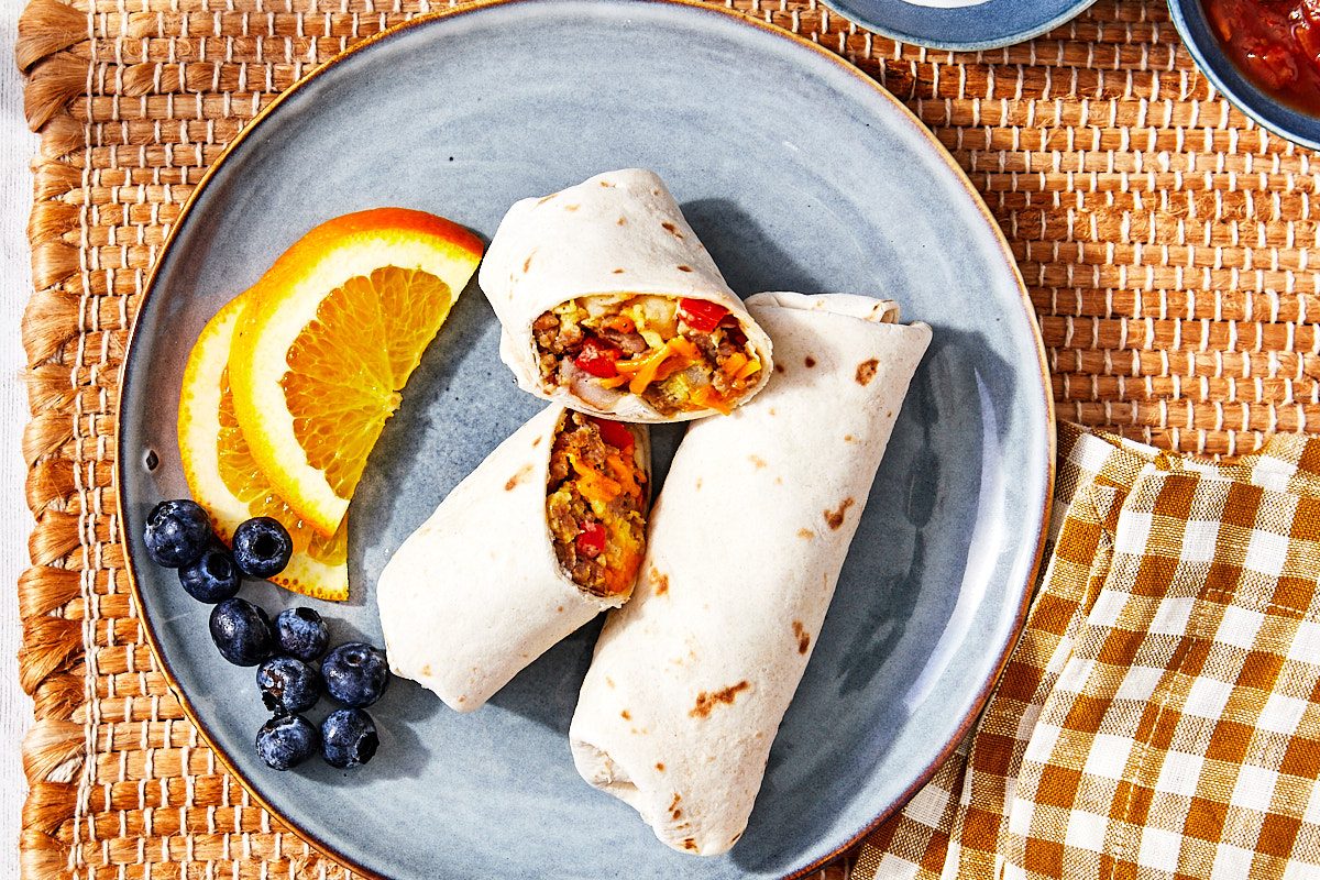 Freezer Breakfast Burritos Hero- Close up of plated burritos, one cut in half with filling exposed.