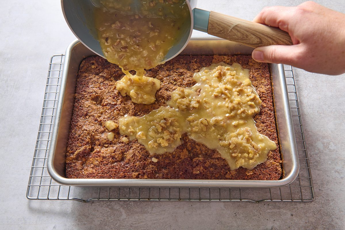 Pouring sauce over the top of the still-warm cake