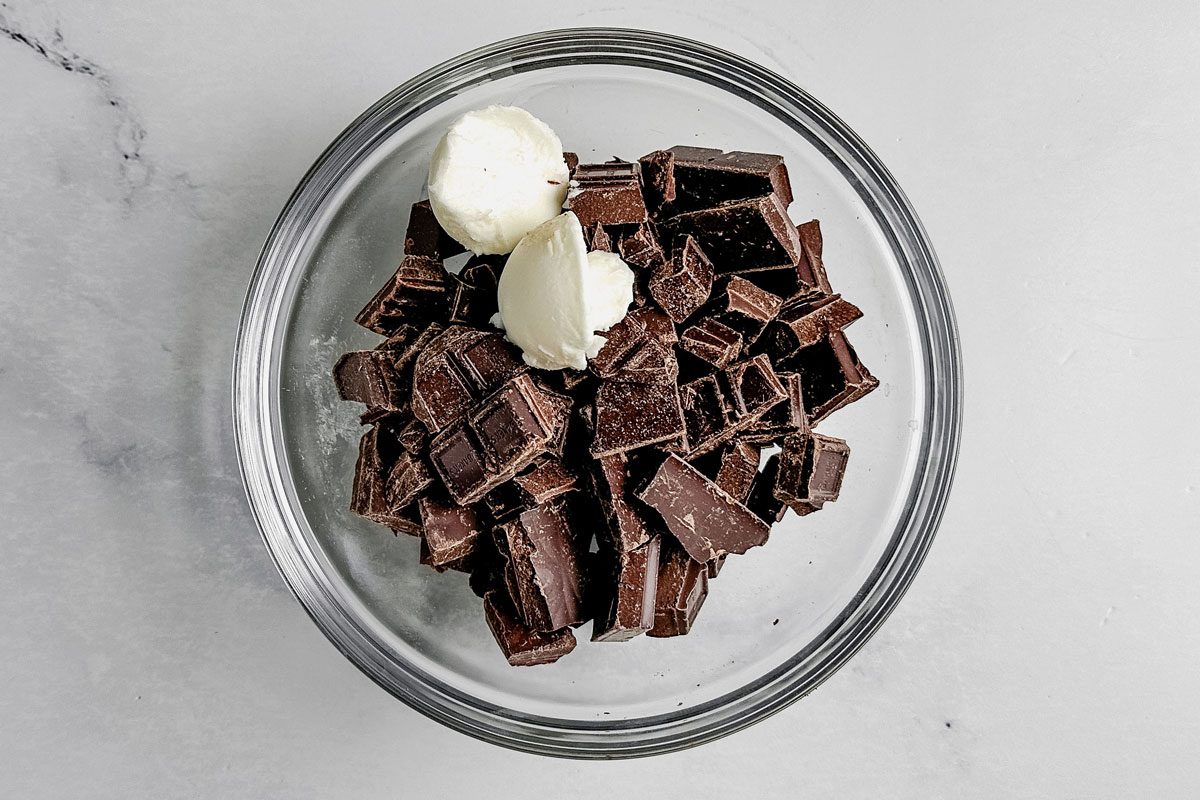 Chopped chocolate and shortening for Taste of Home German chocolate cookies in a glass bowl on a marble surface.
