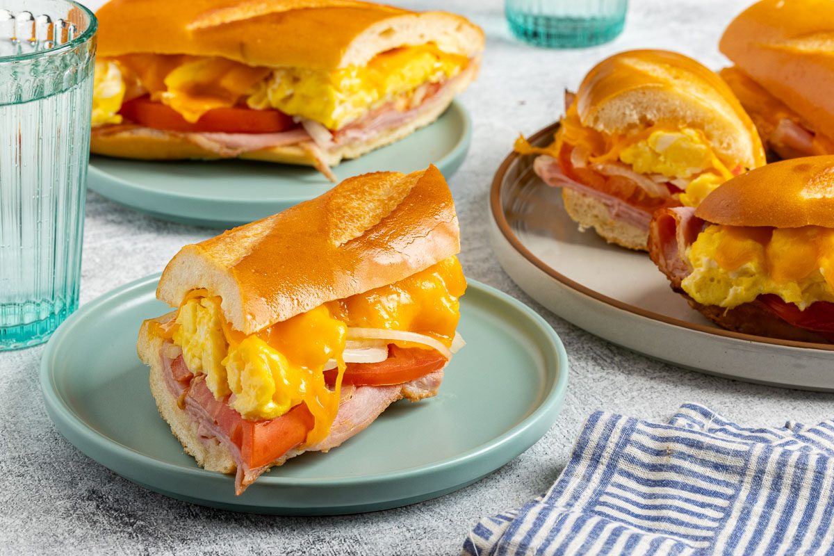 Taste of Home Ham Egg and Cheese Sandwich recipe photo of the sandwich cut into slices and set on a serving platter and plates.