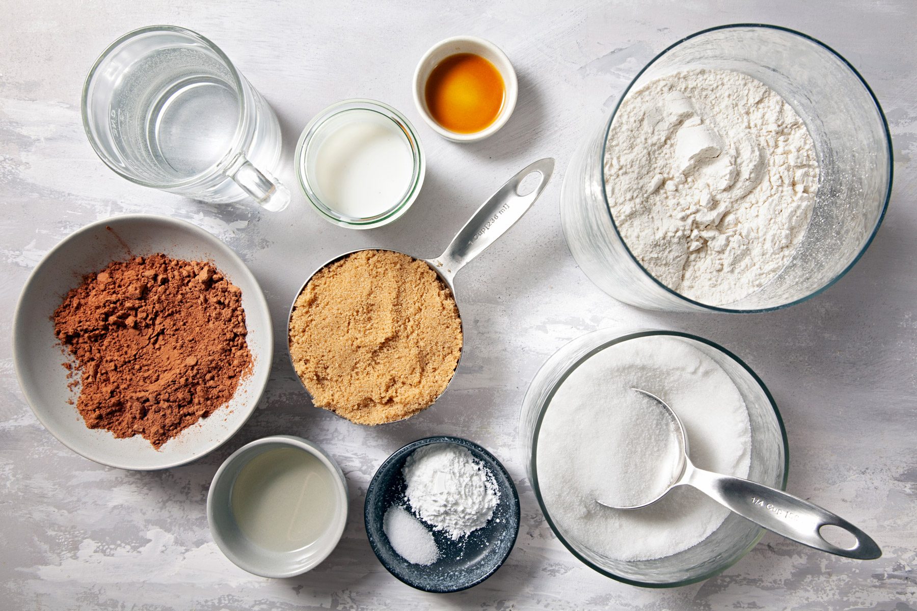 Top view of flour, sugar, baking cocoa, baking powder, salt, milk, oil and vanilla extract.