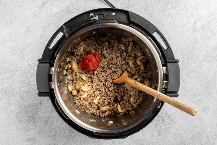 Taste of Home Instant Pot Beef Stroganoff recipe photo of the tomato paste, beef consomme, mushrooms,onions and garlic added to the beef.