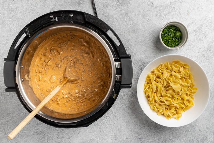 Taste of Home Instant Pot Beef Stroganoff recipe photo of the sour cream added to the pressure and ready to serve with noodles and parsely.