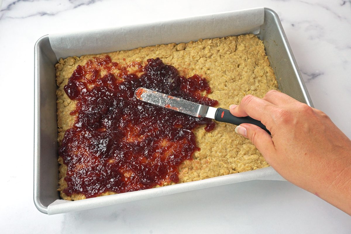 Spreading jam over a cooled crust for lemon cheesecake bars for Taste of Home RMS 15811