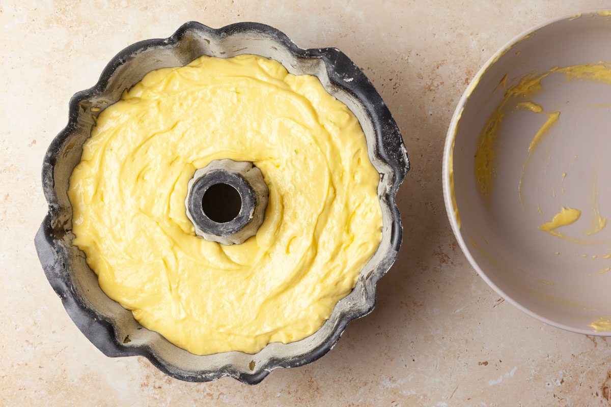 Step 2 of Taste of Home Margarita Cake is to transfer the batter to a greased and floured 10-inch fluted bundt pan. Bake it at 350°F for 45 to 50 minutes or until a toothpick inserted in the center comes out clean. Cool the cake in the pan for 10 minutes before removing it to a wire rack to cool completely.