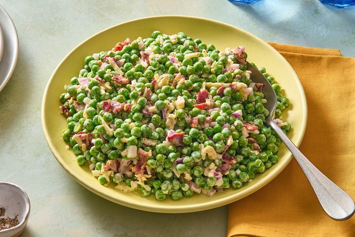 Shot of pea salad with bacon being served with a large spoon
