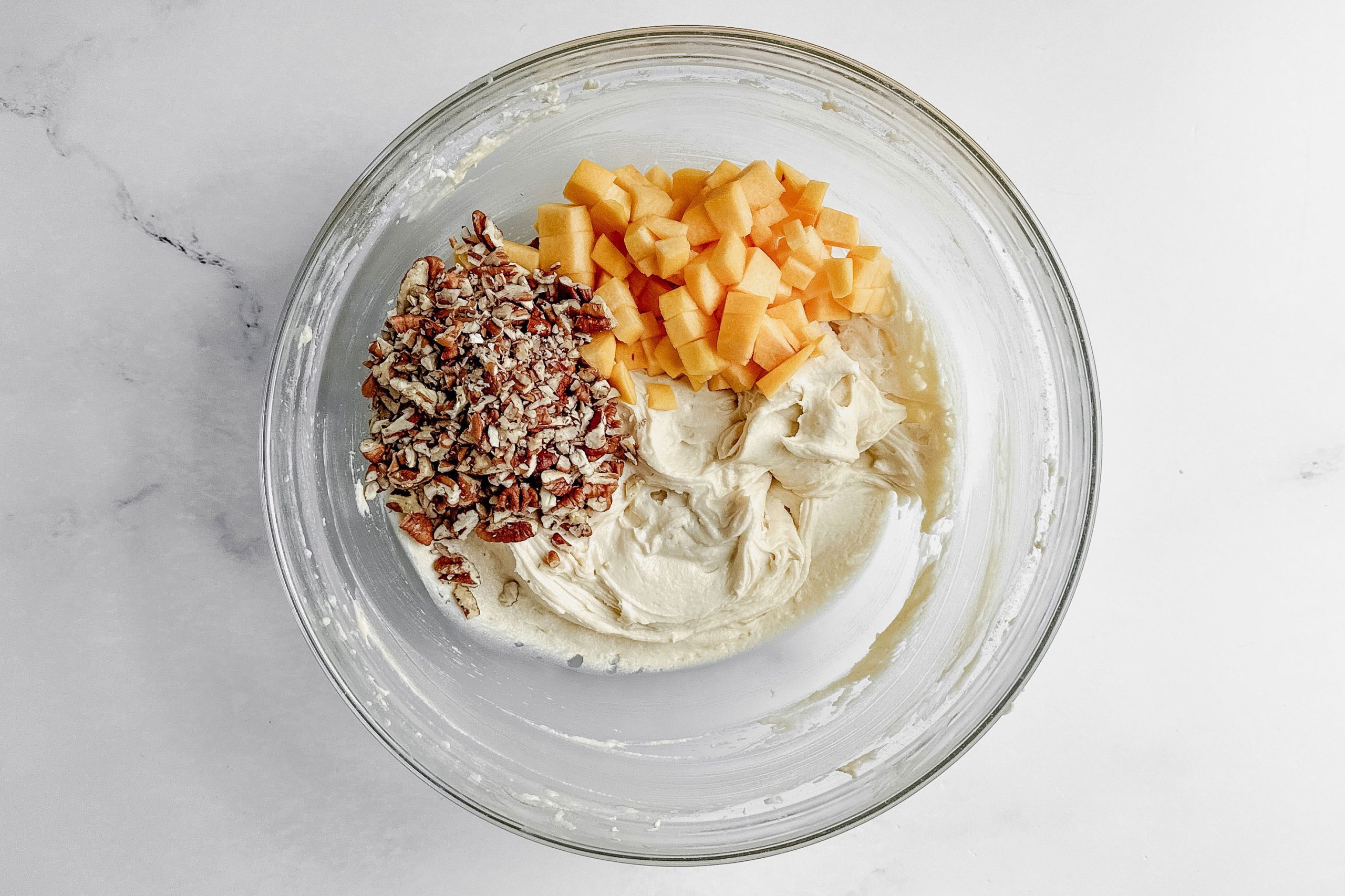 Ingredients for Taste of Home peach muffins in a glass bowl on a marble surface.