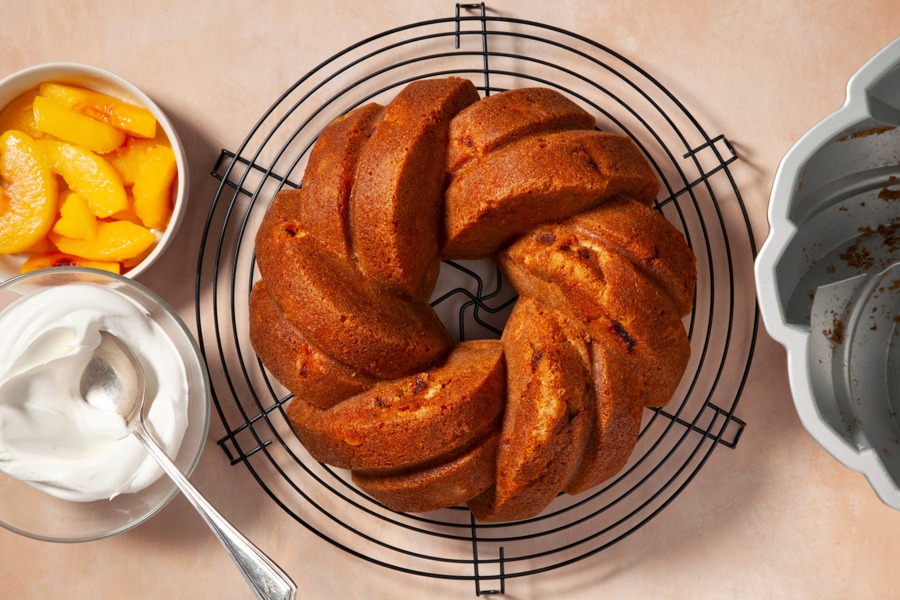 Top view shot of Peach Pound Cake on wire rack with peaches and cream on the side