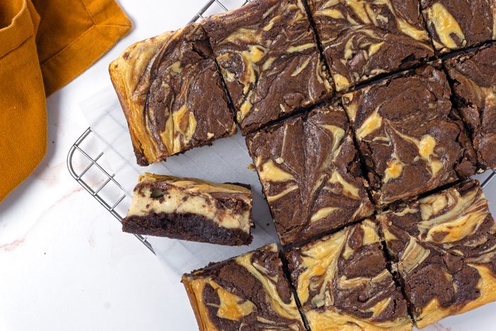 An overhead image of sliced peanut butter swirl brownies on a cooling rack with parchment paper for Taste of Home RMS 11889