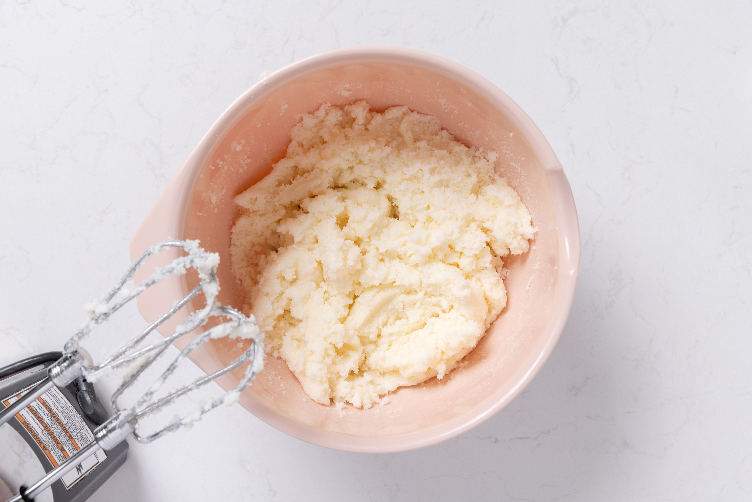 Butter and sugar being creamed in mixing bowl.