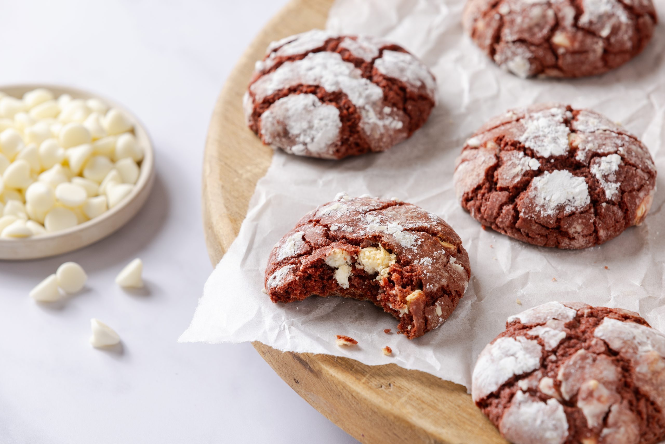 Red velvet crinkle cookies served on wooden board layered with parchement paper.