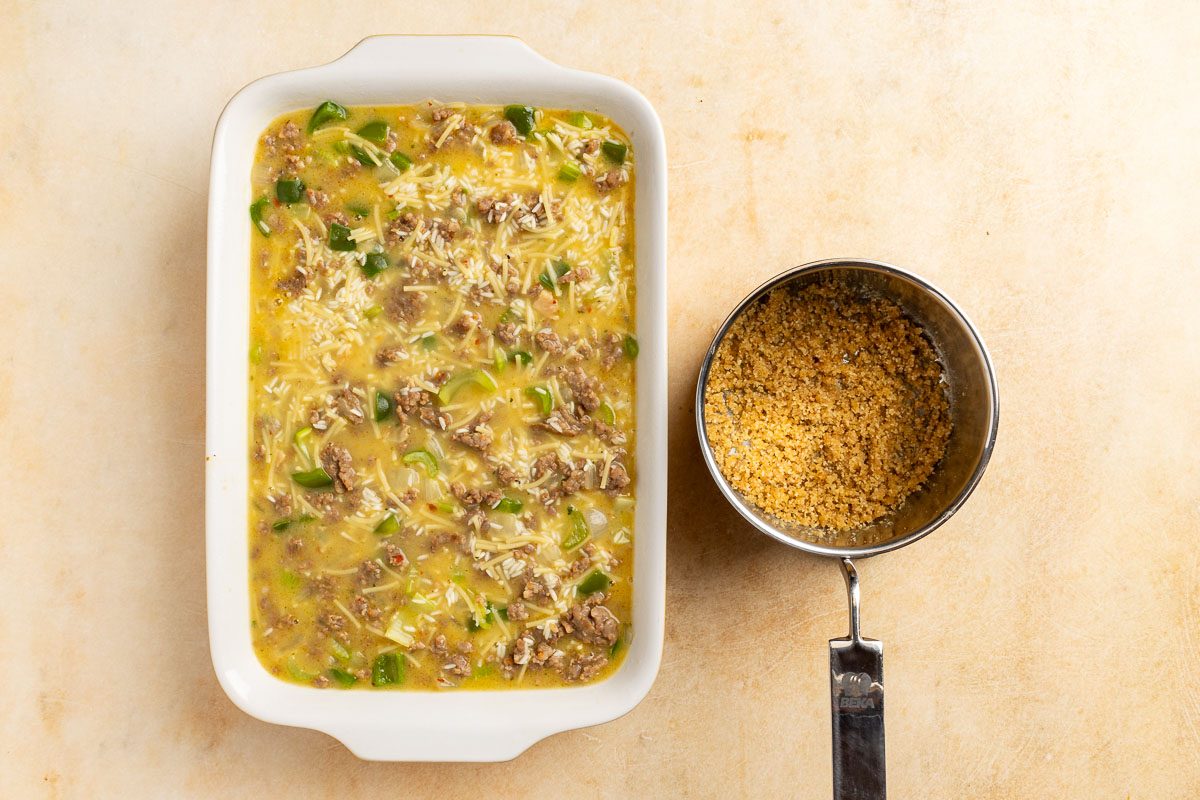 Taste of Home Sausage Rice Casserole recipe photo of casserole mixture poured into a baking dish with the buttered bread crumbs in a saucepan.