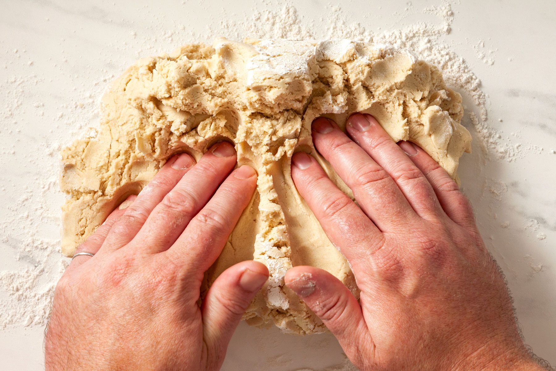 A person's hands can be seen kneading the dough.