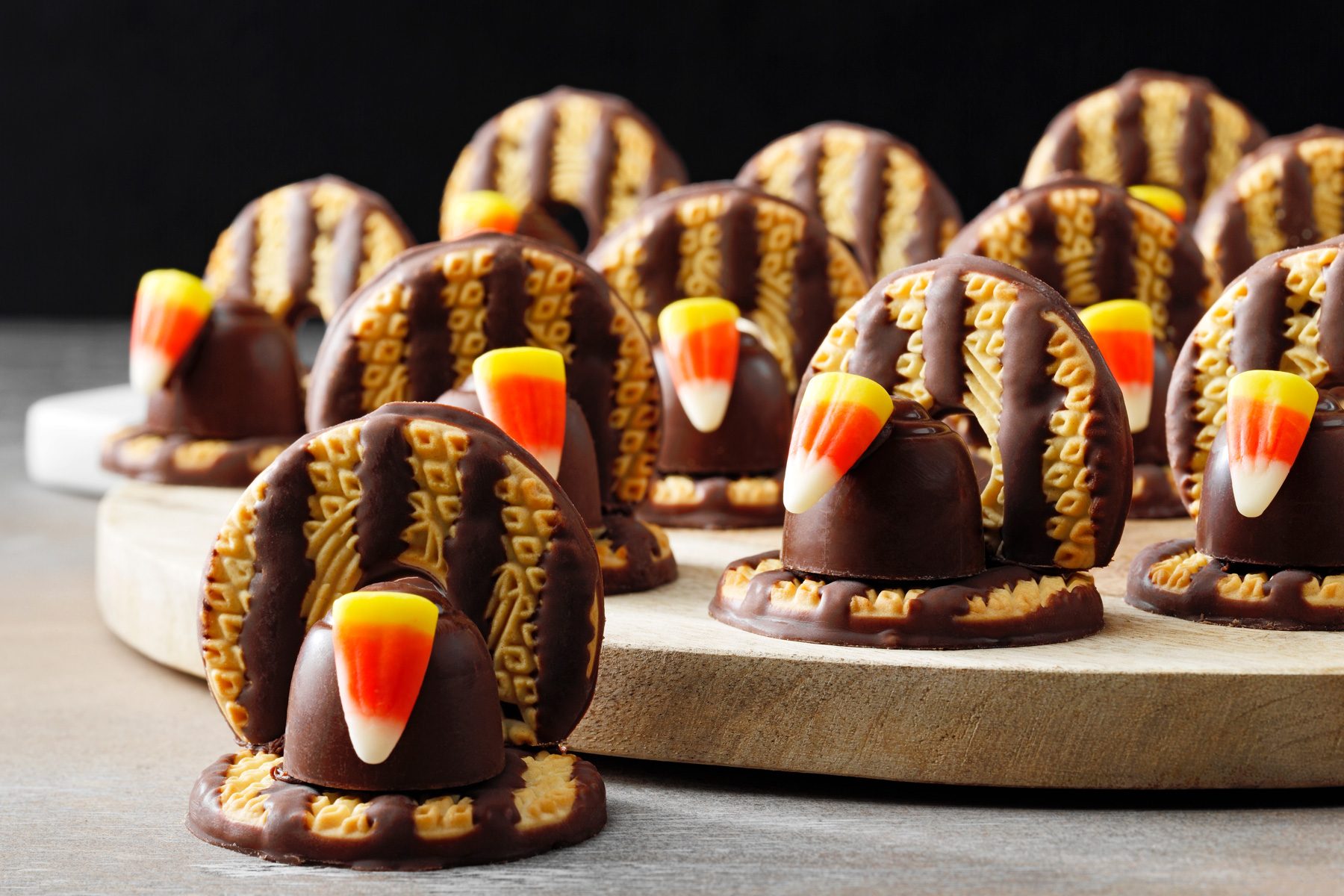 A wooden board of chocolate-covered turkey cookies.