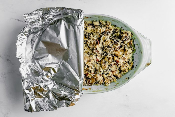 Taste of Home wild rice casserole in a pyrex dish covered with foil on a marble surface.