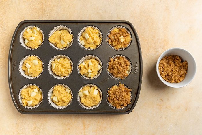 Taste of Home Apple Muffins recipe photo of filling the muffin tin with batter and topping with streusel.