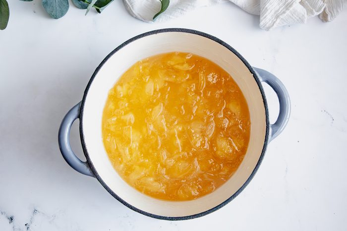 Cooked apple jam for Taste of Home in a crockpot on a marble surface.