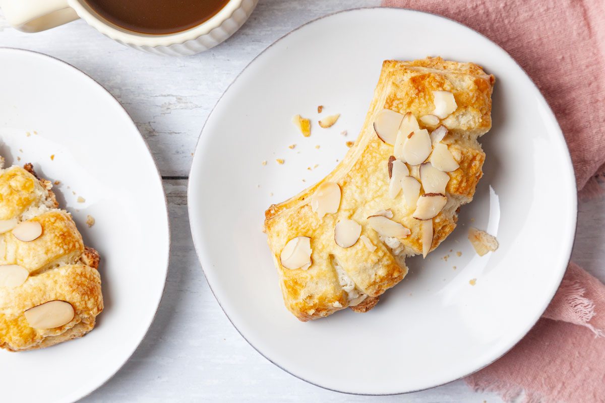 Two Taste of Home Bear Claws on white app plates, pink linen, coffee cup