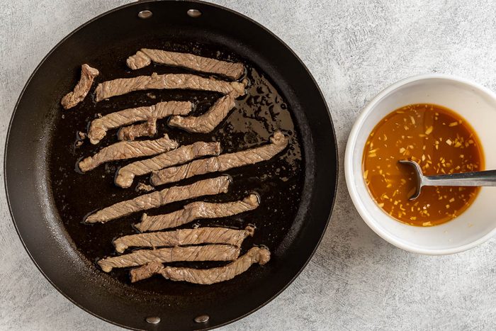 Taste of Home Beef with Broccoli Recipe photo of the brown beef strips and the precooked sauce in a seperate bowl.