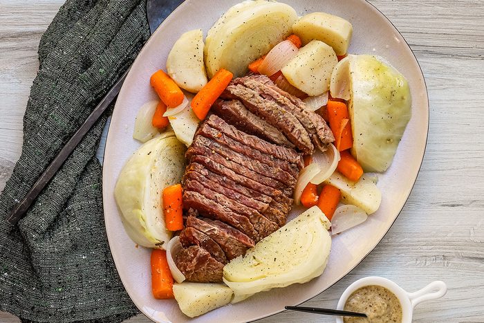 A corned beef boiled dinner with potatoes, carrots, and cabbage, arranged on a large platter.