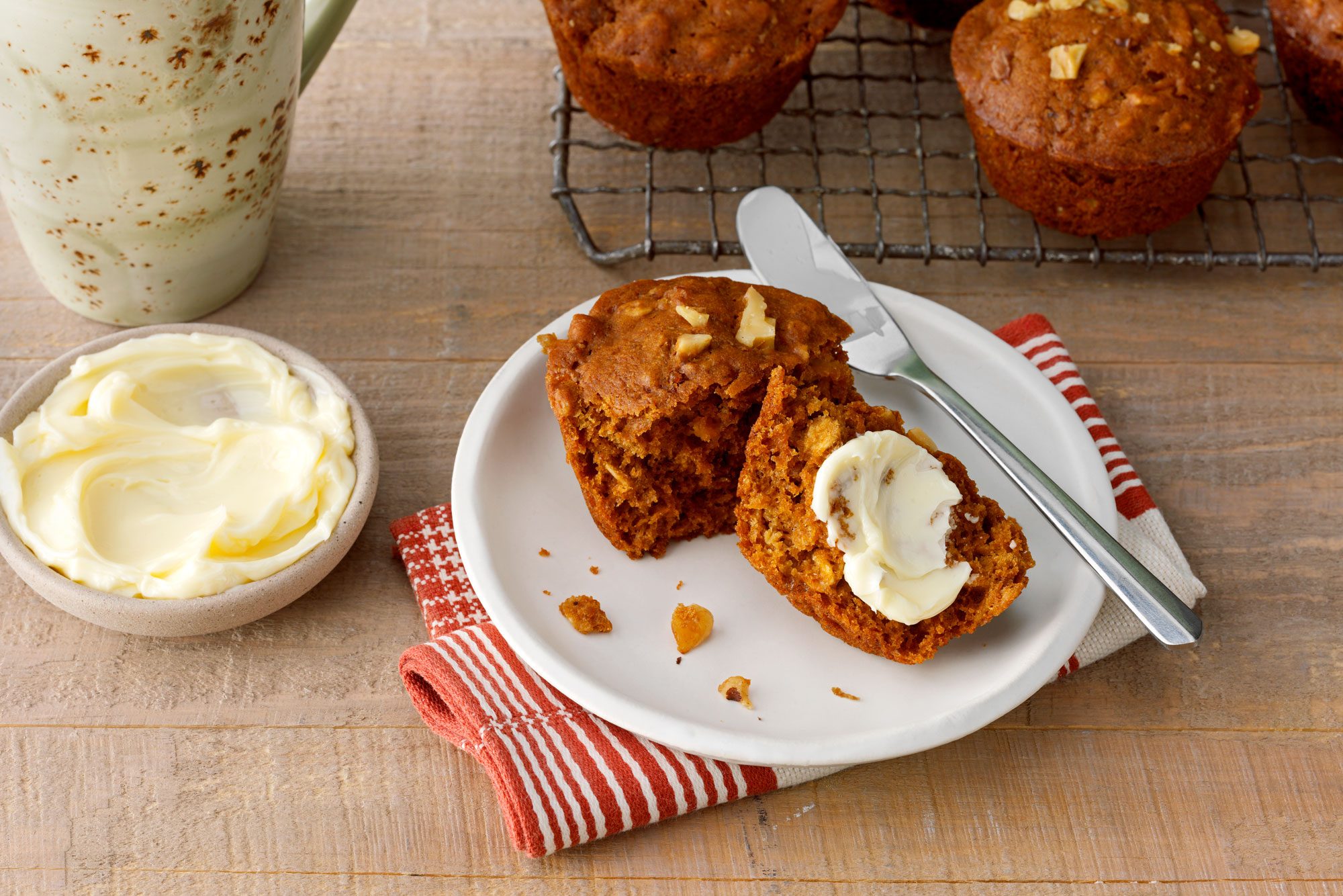 Bran Muffin Served on a plate; knife; kitchen napkin; wooden surface;