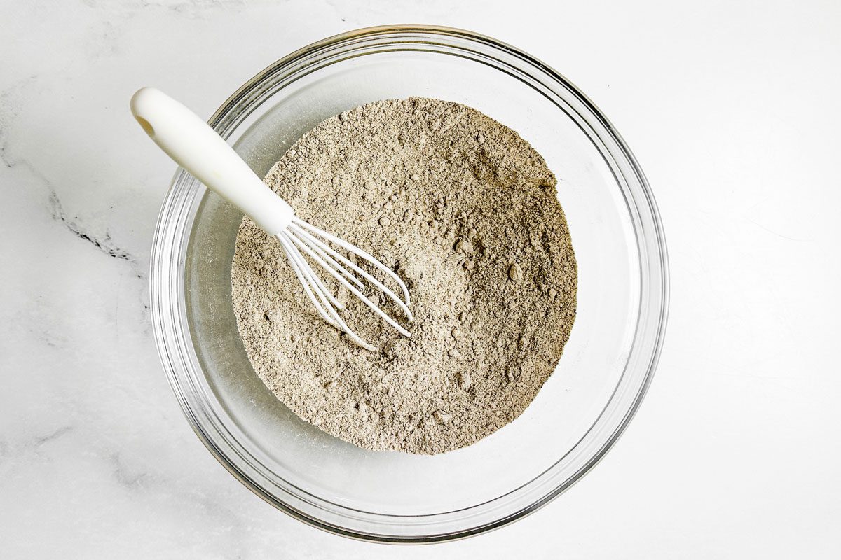Dry ingredients for Taste of Home Buckwheat Pancakes in a glass bowl with white whisk