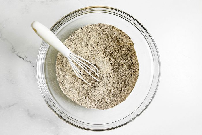 Dry ingredients for Taste of Home Buckwheat Pancakes in a glass bowl with white whisk