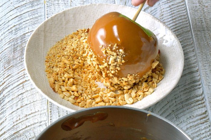 Roll bottoms of dipped apples into chopped peanuts