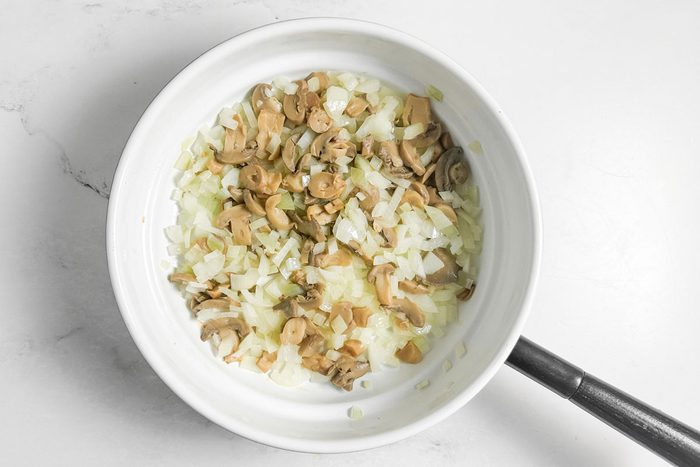 Mushrooms and onions for Taste of Home Chicken Manicotti in a white skillet