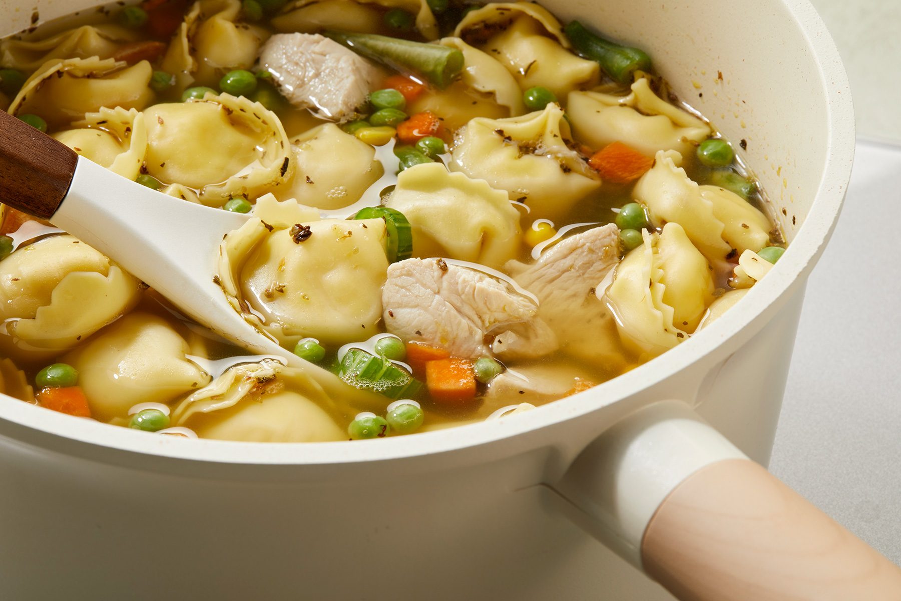 3/4th shot of chicken tortellini soup in a bowl