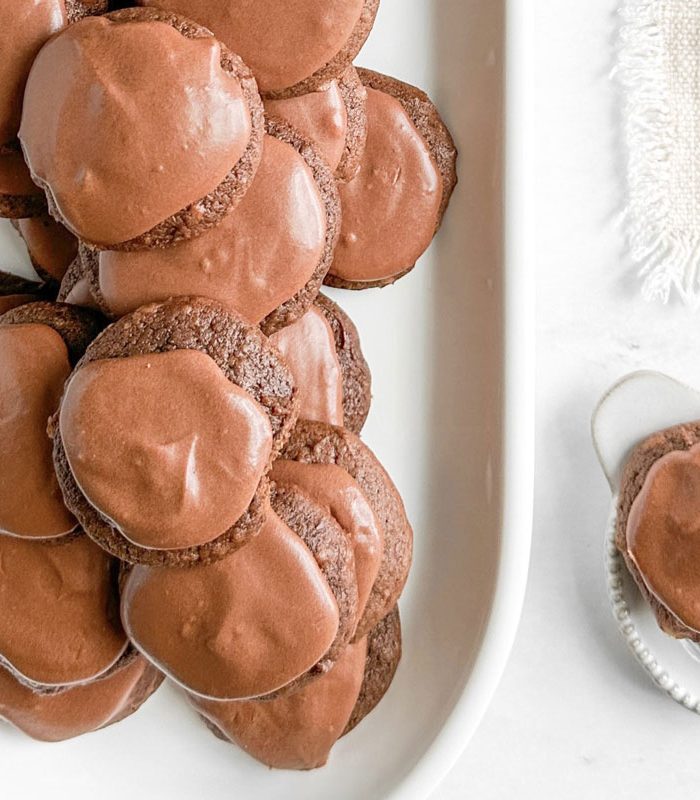 Taste of Home Chocolate Drop Cookies on white ceramic plates next to a linen napkin on a marble surface