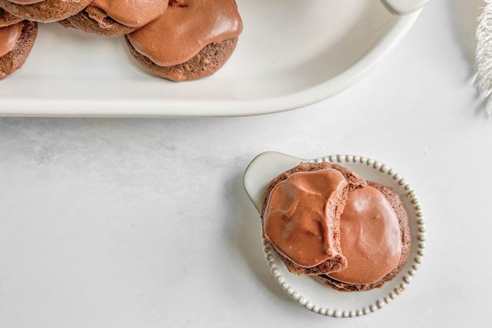 Taste of Home Chocolate Drop Cookies on white ceramic plates next to a linen napkin on a marble surface