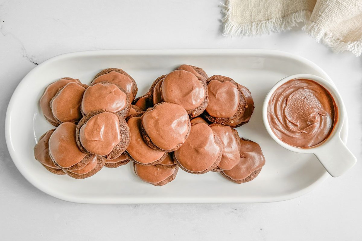 Taste of Home Chocolate Drop Cookies on white ceramic plates next to a linen napkin on a marble surface