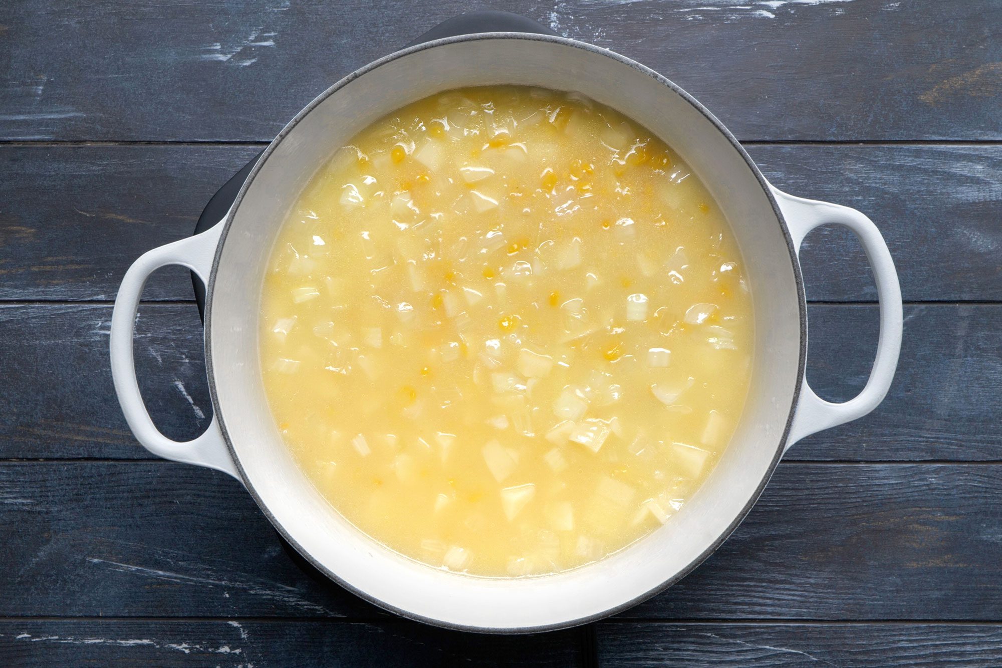 overhead shot of boiled potato and corn in a dutch oven