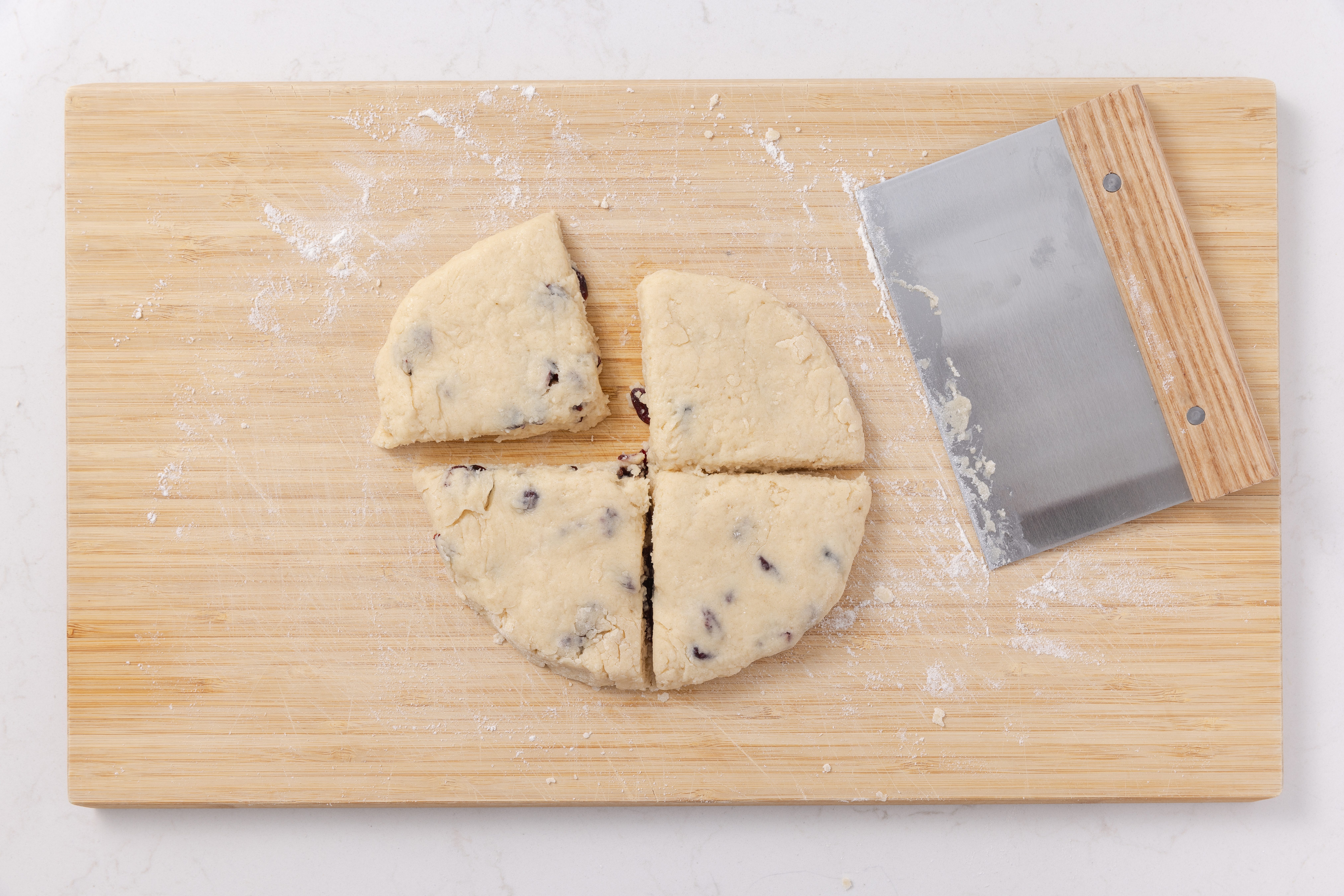 Dough being cut into four pieces on floured surface.