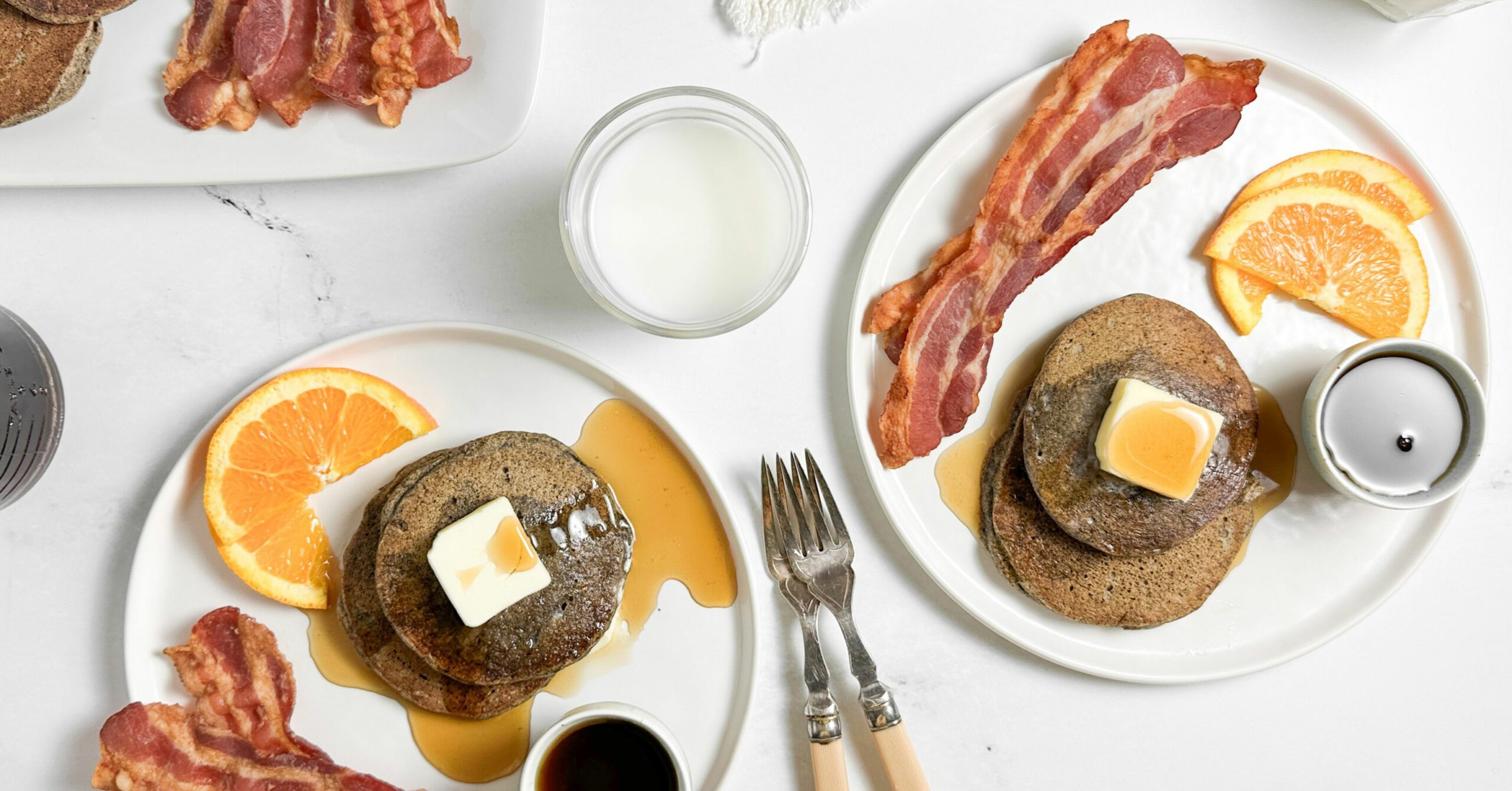 Taste of Home Buckwheat Pancakes with bacon and orange slices on white plates