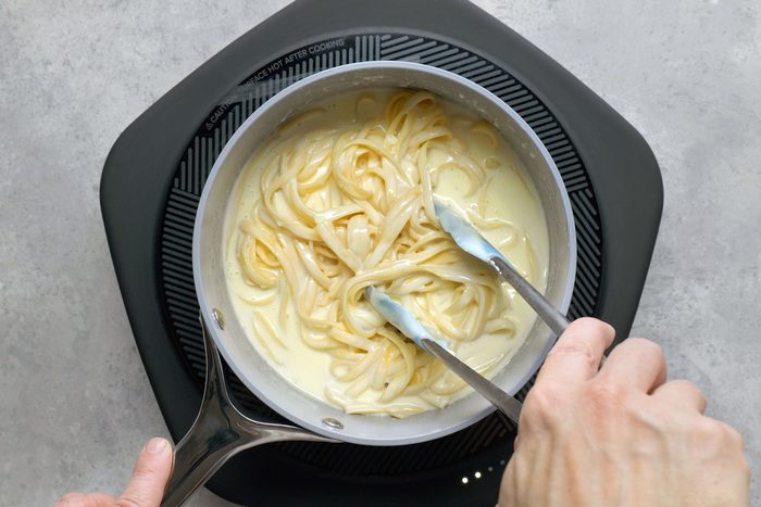 Added fettuccine into the cream in the saucepan using tongs