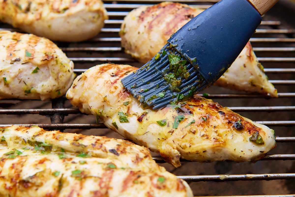 Brushing the marinade on the chicken breasts on the grill